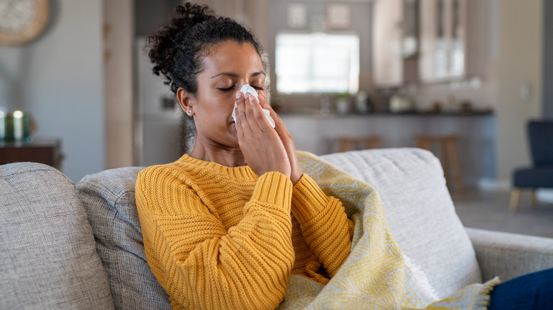 Woman holding tissue to face