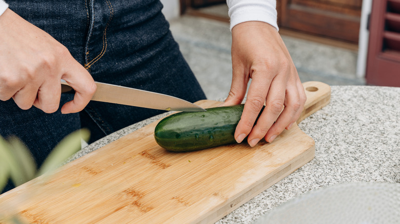 A person cuts a cucumber lengthwise