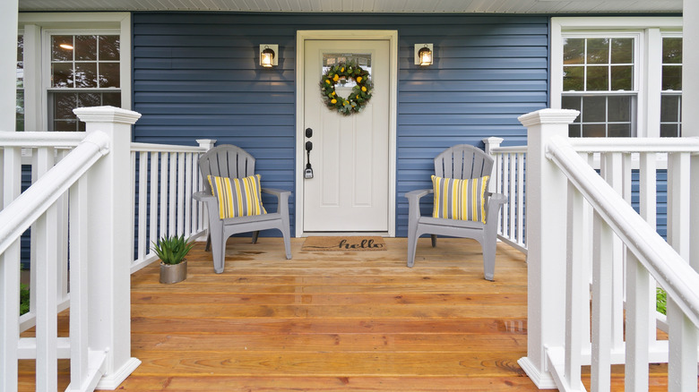 A front porch with a wood deck and lounge chairs by the front door