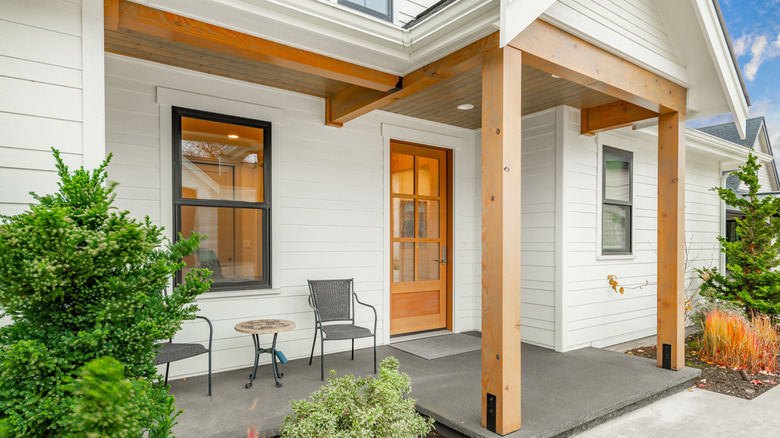 A front porch with a seating area and wooden beams installed over the front door