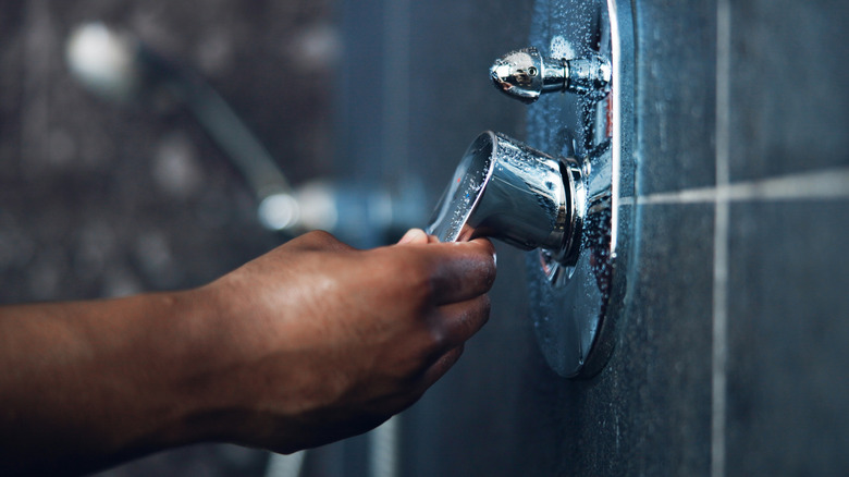 A man's hand turning on the shower
