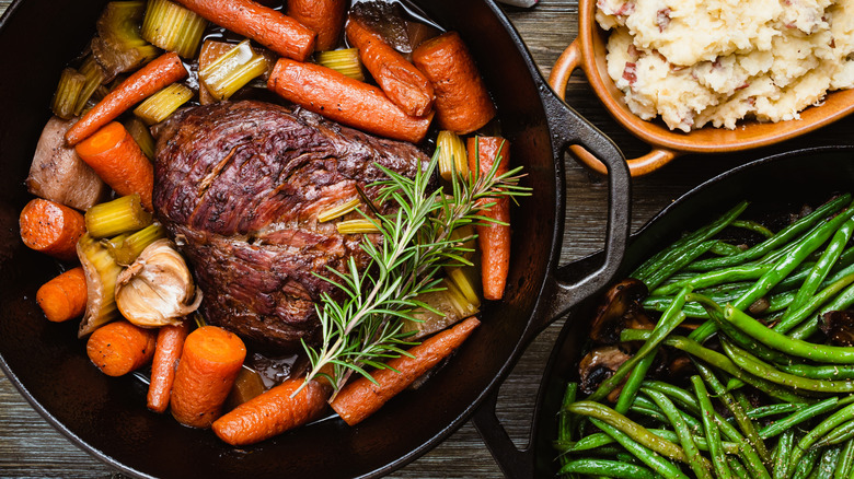 A pot roast and green beans cooked in a cast iron pans