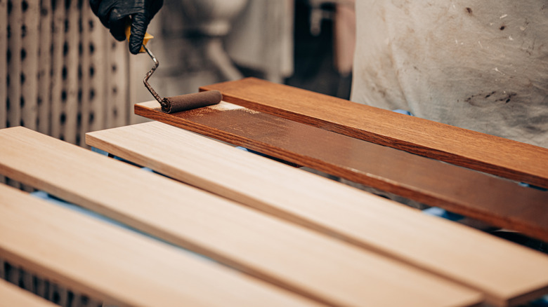 Hand rolling wood stain on boards