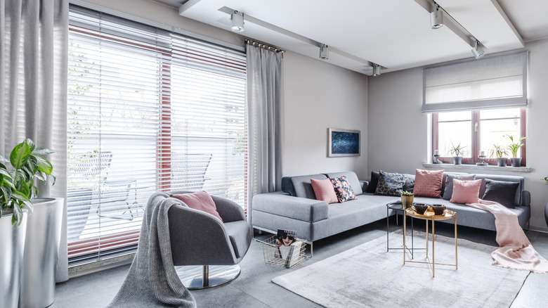 Living room with a variety of window treatments -- blinds, shade, curtains.