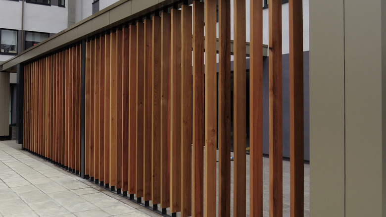 Vertical wood louver fence with metal columns framing it
