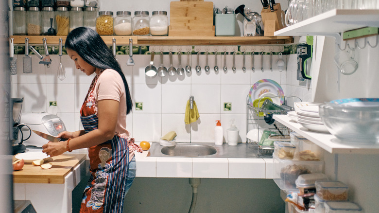 Woman prepares food in a small but organized kitchen