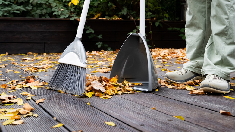 Sweeping leaves with a broom and dustpan