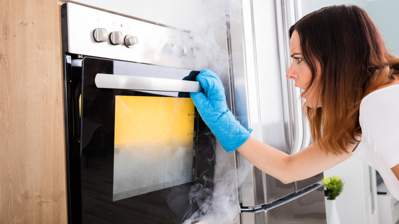 woman looking at smoking oven