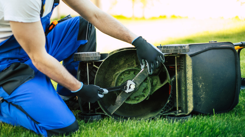 man replacing a mower blade