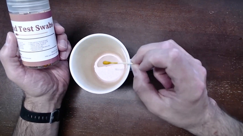 Person swabbing a mug for lead