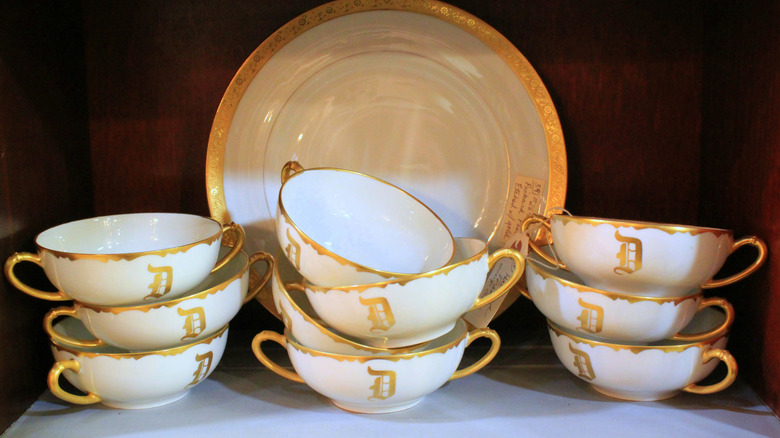 A set of monogrammed white cups in front of a white plate