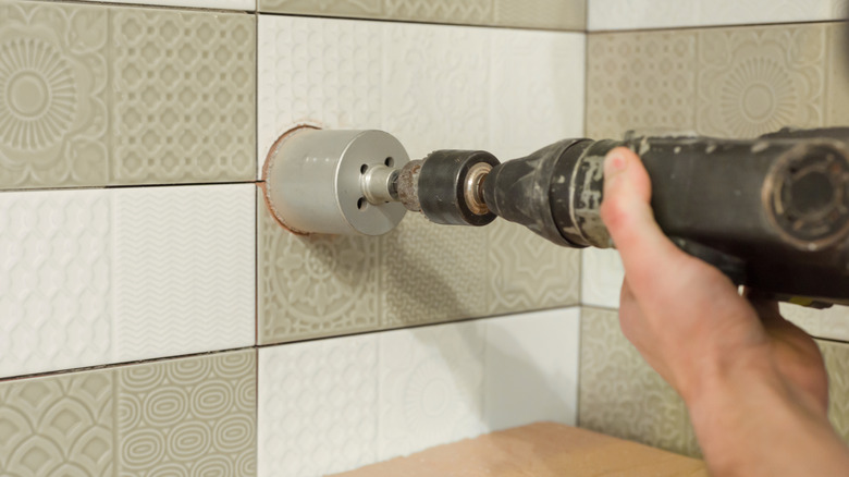 person using drill with diamond drill bit on tiles