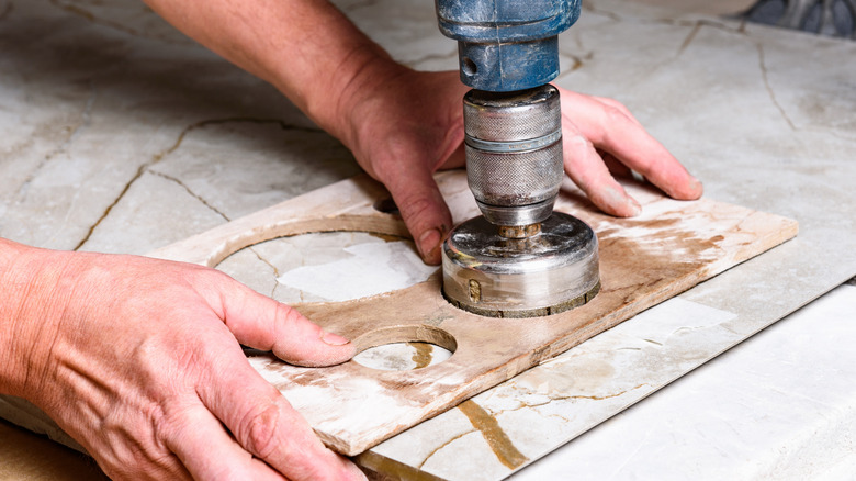 person holding tile with holes made by diamond drill bit
