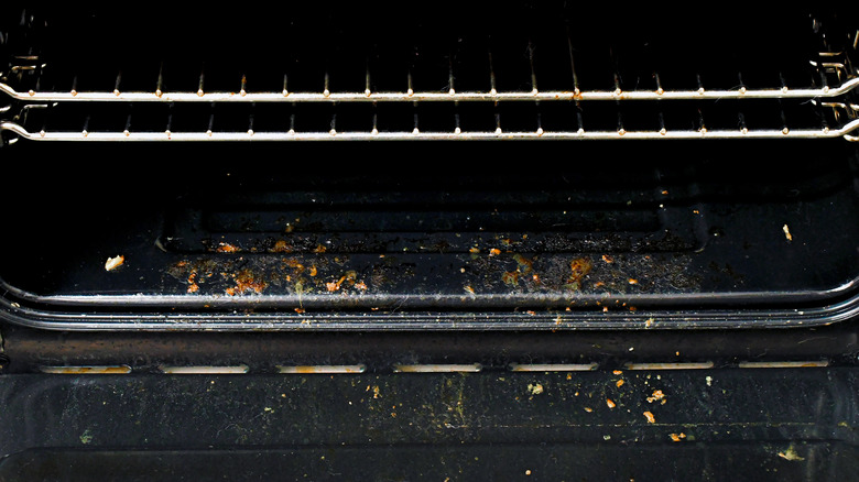 Close-up of the inside of a dirty kitchen oven full of crumbs