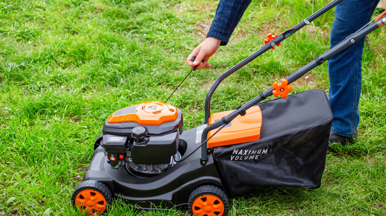 A person starting a lawn mower