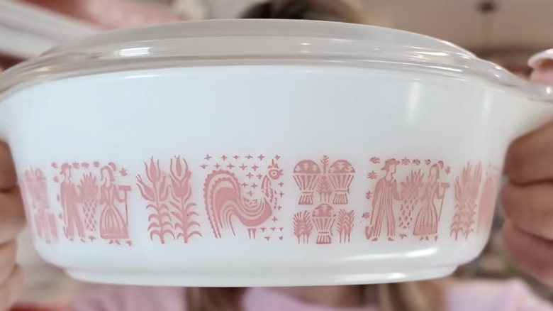 A person holds up a rare pink butterprint Pyrex dish