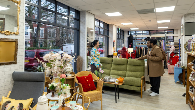 A smiling woman and man shop for thrifted furniture.