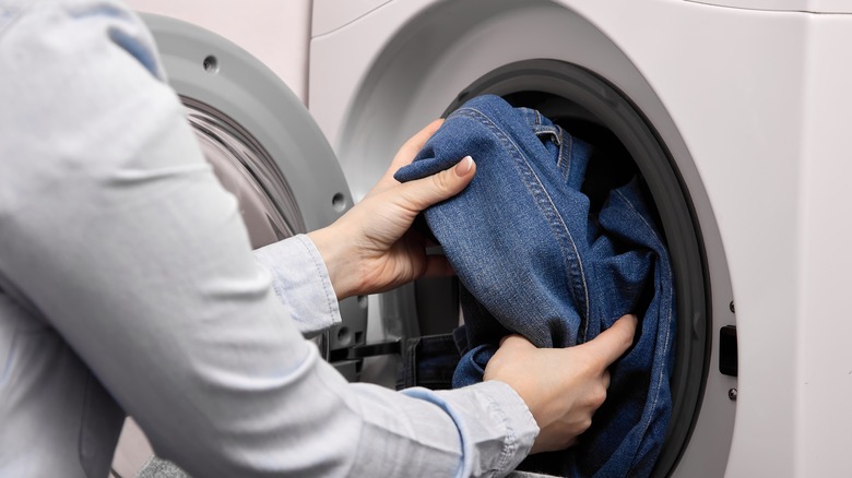 Person adding jeans to wash