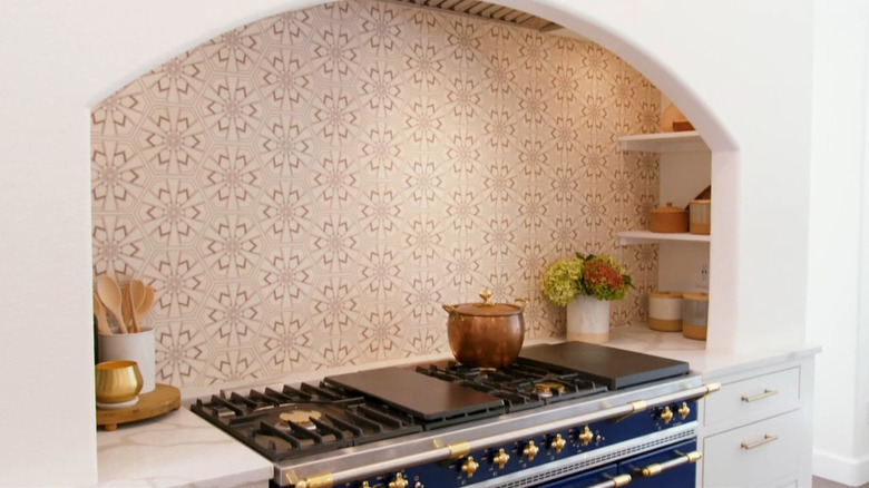 A woman and a man standing in front of a stylish oven range.