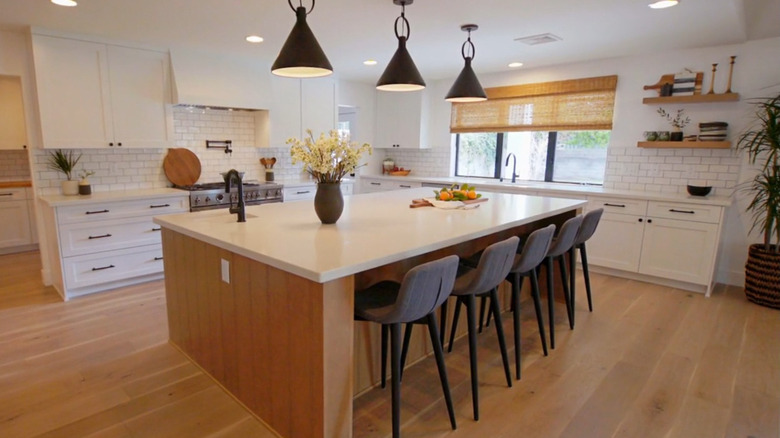 A modern white kitchen with black pendant lights.