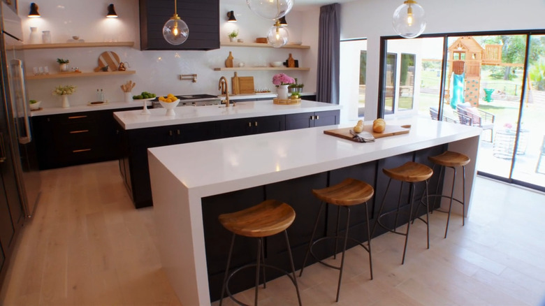 A kitchen with a large island and black cabinets