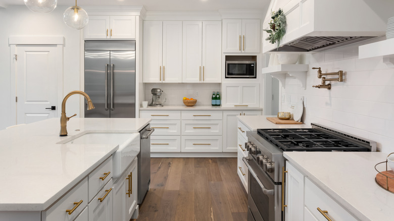 A modern white kitchen with mixed metal finishes.