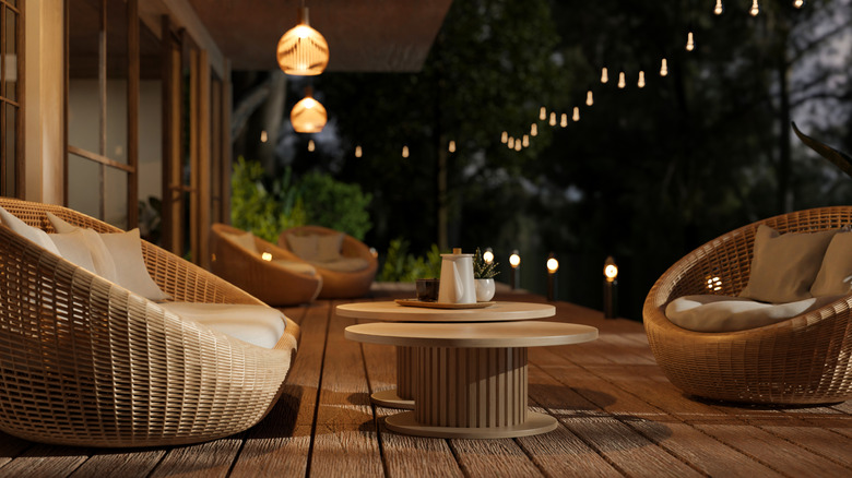 A deck rattan table and chairs, string lights, and lanterns, at night