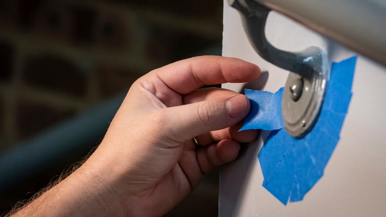 person applying painter's tape on fixture