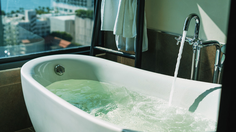 An elegant bathtub partially filled with water coming from the faucet.