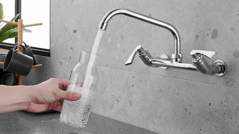 person using wall-mounted faucet