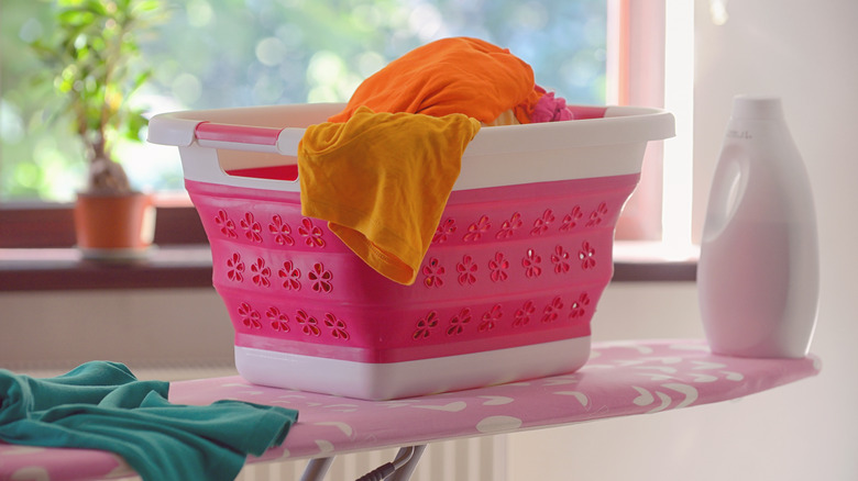 Pink collapsible laundry basket on ironing board