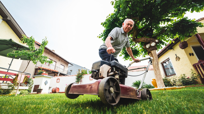Man attempting to start a gas-powered lawn mower