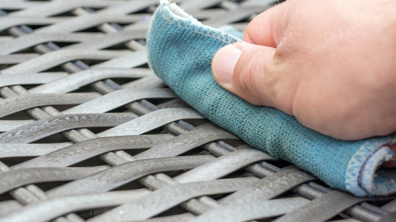 Hand wiping outdoor furniture with cloth