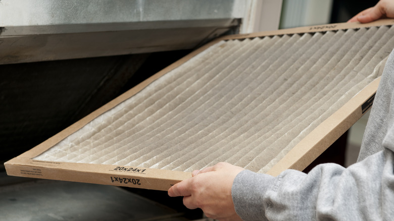 A person holding a dirty AC filter