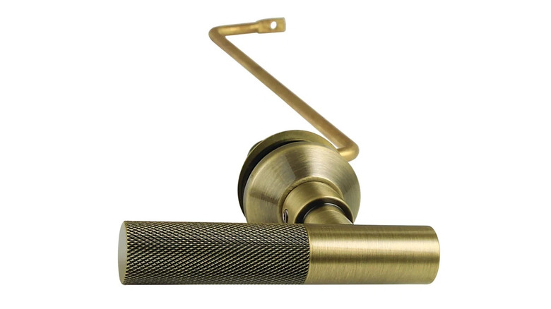 A brushed brass toilet flush handle is shown in a detail shot