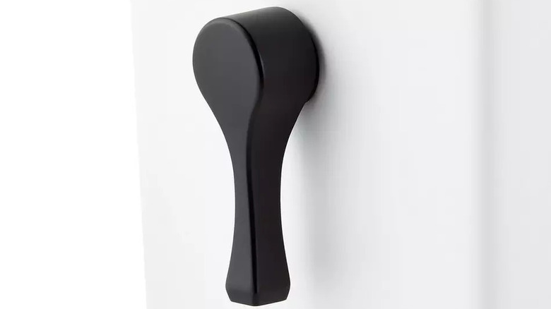 A matte black side-mount toilet flush handle is installed on a white tank