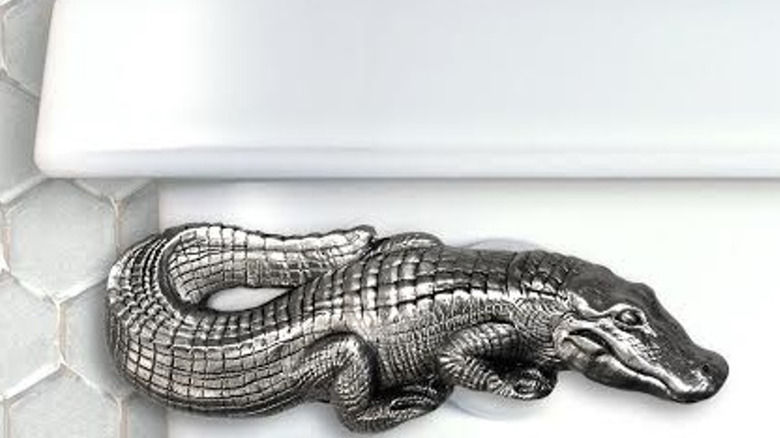 An Alligator toilet flush handle in satin pewter finish is installed on a white tank