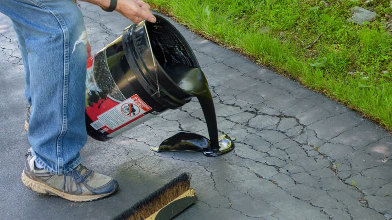 Pouring asphalt sealant on a driveway to repair cracks