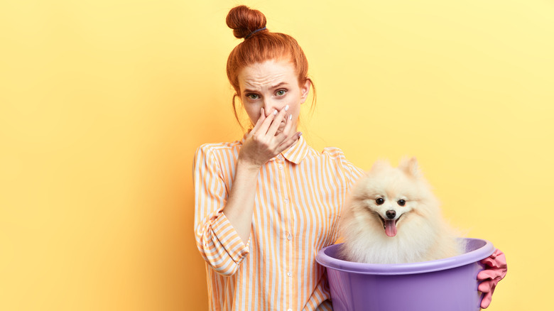 Woman holding dog plugging nose