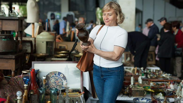 A woman examining vase in a thrift market