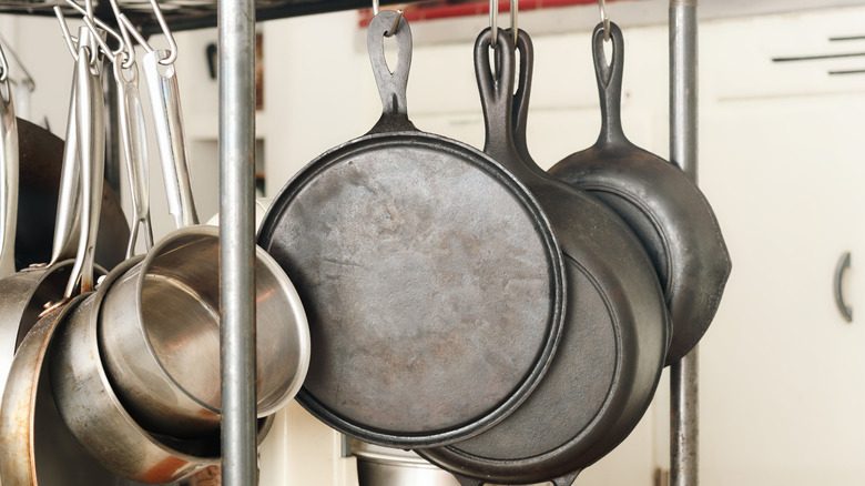 a collection of cast iron pans and pots hanging on hooks