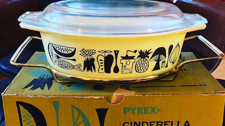 Pyrex Mod Kitchen casserole dish with original wire frame and lid on top of the original box