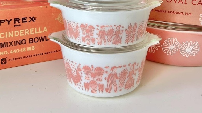 Closeup of Pyrex pink and white Butterprint dishes on a shelf next to their original packing boxes