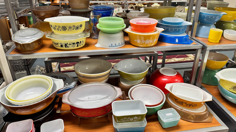 An assortment of vintage Pyrex mixing bowls, casserole dishes, and baking pans in a store.