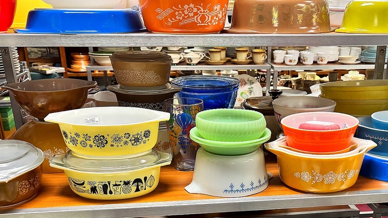 Various Pyrex bowls fill a shelf in a secondhand shop