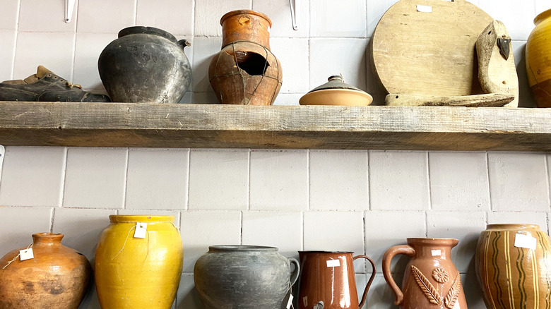 Assortment of old pottery on shelves for sale.