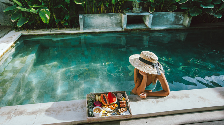 woman in pool with tray of fruits