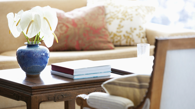 A traditional but cozy living room with a chair, beige sofa, blue vase, and wood table