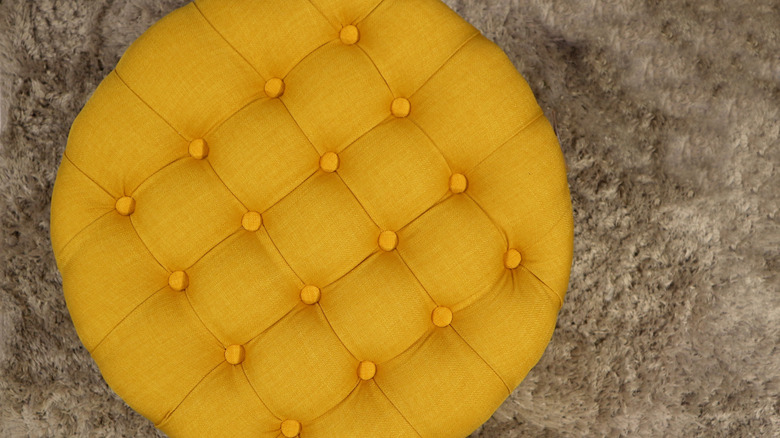 A tufted yellow floor pouf is seen from overhead.