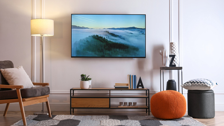A casual living room includes an orange pouf and black storage among livingroom furnishings